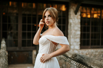 Fototapeta premium Beautiful bride portrait standing on wooden bridge in front of stone building