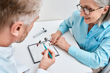 Hearing aids. Behind-The-Ear hearing aids are recommended by audioprosthetist to his woman patient...