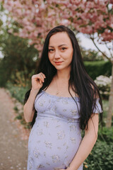 Fototapeta premium portrait of pregnant woman in park with magnolia tree