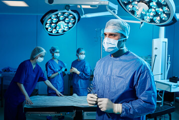 Portrait of male surgeon in operating ward with medical team. Surgery department