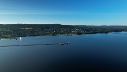High angle view above blue Siljan Lake and a pier. Town Rättvik by the mountain. Blue sky with mountains and forests in the background. Panorama cityscape view