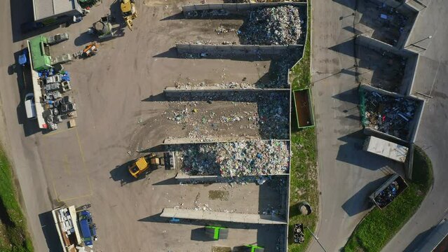 Waste transfer station area, skid steer loaders transporting trash material, top down aerial shot. Recycling and waste center concept.