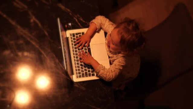 Overhead view of a cute funny little girl pretending to work on the laptop