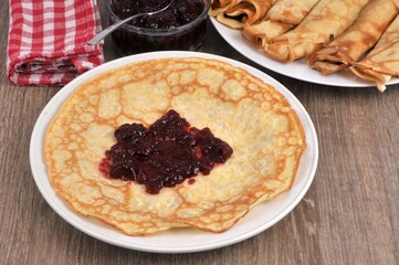 Crêpe avec de la confiture dans une assiette et un ramequin de confiture