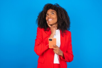 Image of a thinking dreaming young businesswoman with afro hairstyle wearing red over blue...