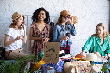 Young women choose things at flea market. Casual clothes, shoes, hats, bags, jewellery. Idea of exchange your old wardrobe for new. Eco friendly cloth concept. Zero waste shopping, reduce and reuse