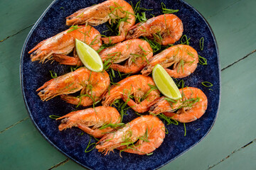 Shrimp sauteed with garlic and oil in a dark blue dish on a green painted wooden table. Brazilian food widely consumed on the coast.