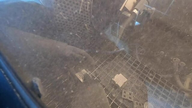 Shot blasting. Shot blasting of model printed on 3D printer from polyamide powder. A worker in sealed rubber gloves cleans the object by shot blasting in a shot blasting chamber. Industrial machine