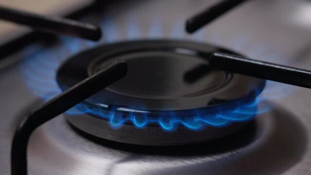 Fire lights up close up in the burner of the gas stove. A stove uses combustible or natural gas from the city gas network or liquefied gas as fuel.