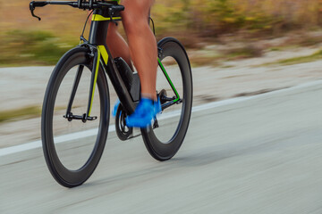 Close up photo of an active triathlete in sportswear and with a protective helmet riding a bicycle....