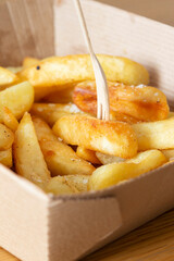 Chip shop chips takeaway in a cardboard tray with a wooden fork. Biodegradable plastic free eco...