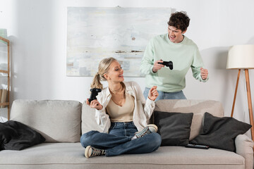 KYIV, UKRAINE - OCTOBER 24, 2022: joyful young couple holding joysticks while playing video game 