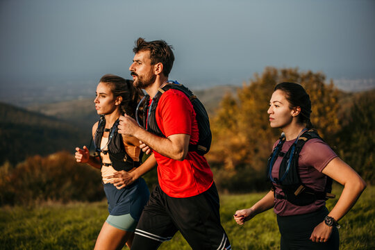 Three runners sprinting outdoors - Sportive people training in a nature area, healthy lifestyle, and sports concepts. High quality photo