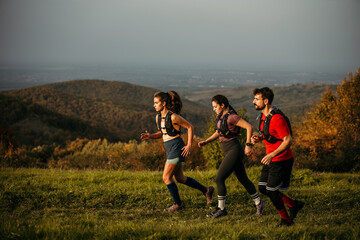 A diverse group of young people exercises outdoors, preparing for a mountain trail. They are wearing sports clothing and a trail running vest © La Famiglia