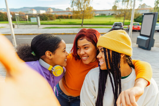 three young hispanic girls taking a picture as they leave class. latina friends celebrating friendship.