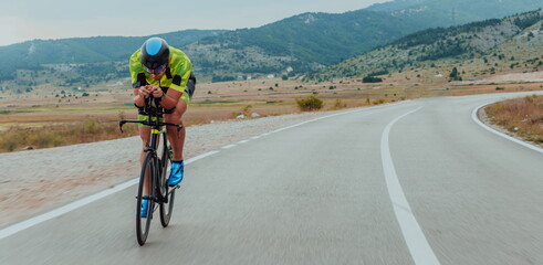 Full length portrait of an active triathlete in sportswear and with a protective helmet riding a bicycle. Selective focus 