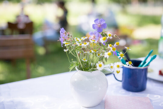 Familienfest im Gr&uuml;nen, Wildblumen auf dem wei&szlig;en Tischtuch