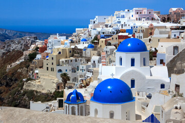 City of Oia on Santorini Island (part of the Cyclades). Church with blue dome and other colorful...