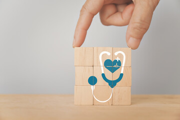 For world health day, health check up and insurance, wellness, wellbeing concept. Hand complete wooden cube block with stethoscope and heart icon