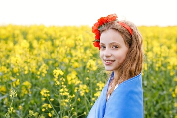 Pray for Ukraine. Child with Ukrainian flag in rapeseed field. Girl holding national flag praying for peace. Happy kid celebrating Independence Day.