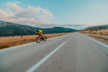 Full length portrait of an active triathlete in sportswear and with a protective helmet riding a bicycle. Selective focus 