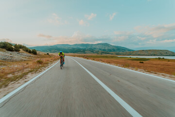Full length portrait of an active triathlete in sportswear and with a protective helmet riding a bicycle. Selective focus 