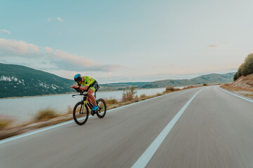 Fototapeta premium Full length portrait of an active triathlete in sportswear and with a protective helmet riding a bicycle. Selective focus 