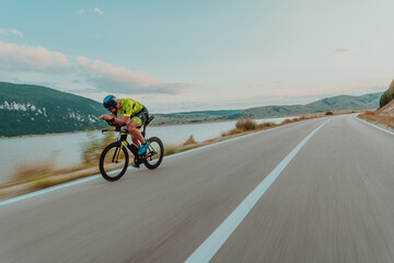 Full length portrait of an active triathlete in sportswear and with a protective helmet riding a...
