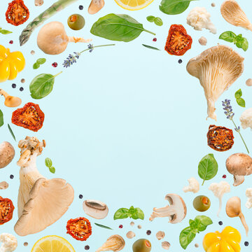 Natural circular frame with oyster mushrooms, champignons, herbs and vegetables on isolated pastel blue background. Minimal creative pattern. Food card concept. Agricultural texture.