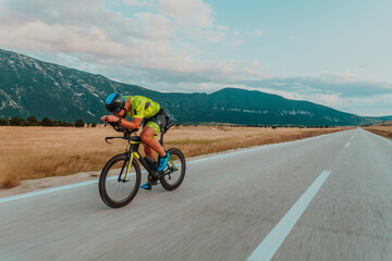 Full length portrait of an active triathlete in sportswear and with a protective helmet riding a bicycle. Selective focus 