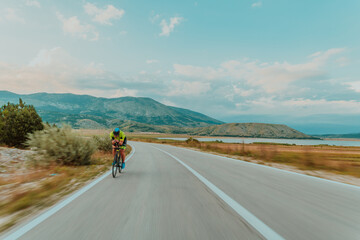 Full length portrait of an active triathlete in sportswear and with a protective helmet riding a...