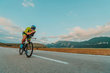 Full length portrait of an active triathlete in sportswear and with a protective helmet riding a bicycle. Selective focus 