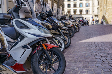 Scooters and motorcycles parked in a perfect row on a street in Italy
