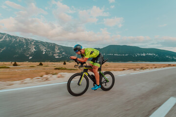 Full length portrait of an active triathlete in sportswear and with a protective helmet riding a...