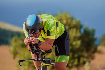 Close up photo of an active triathlete in sportswear and with a protective helmet riding a bicycle. Selective focus