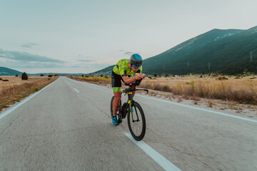 Full length portrait of an active triathlete in sportswear and with a protective helmet riding a bicycle. Selective focus 