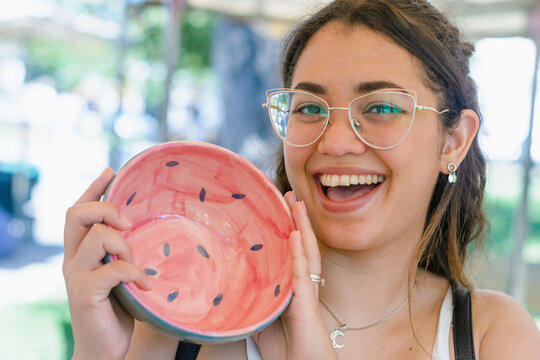 young latin woman happy because she bought a bowl with watermelon colors, at the craft fair.