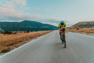 Full length portrait of an active triathlete in sportswear and with a protective helmet riding a...