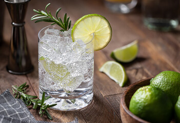 Gin and tonic cocktail with lime. rosemary and ice - 567357345