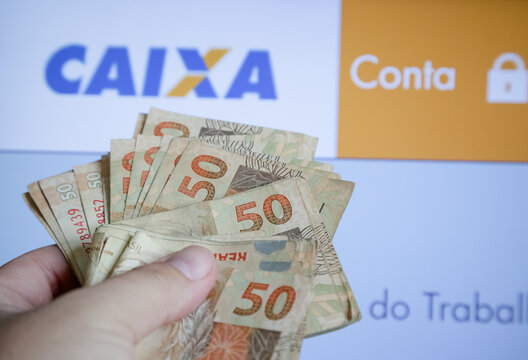 M&atilde;o segurando carteira de trabalho com dinheiro pis pasep do gorverno.
