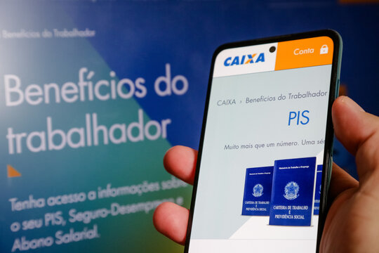 M&atilde;o segurando carteira de trabalho com dinheiro pis pasep do gorverno.