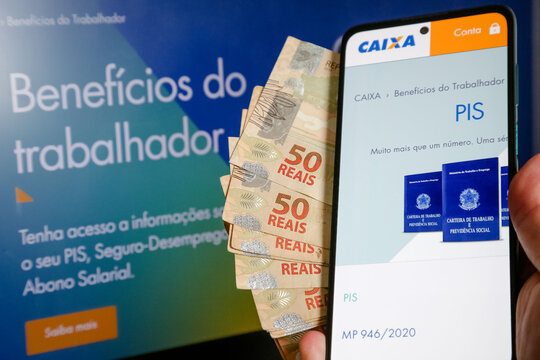 M&atilde;o segurando carteira de trabalho com dinheiro pis pasep do gorverno.