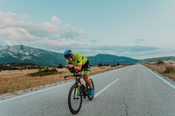 Full length portrait of an active triathlete in sportswear and with a protective helmet riding a bicycle. Selective focus 