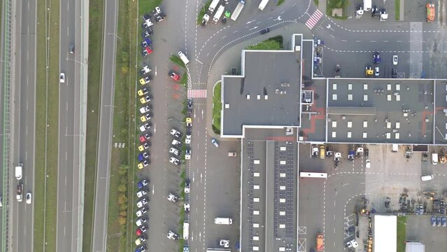 Logistics park with a warehouse and loading hub. Semi-trucks with cargo trailers standing at the ramps for loading/unloading goods at sunset. Aerial hyper lapse.