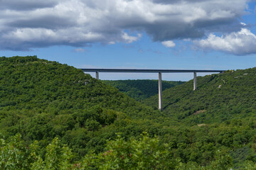 A huge bridge on three supports over a valley between two forested mountains