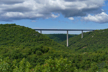 Fototapeta na wymiar A huge bridge on three supports over a valley between two forested mountains