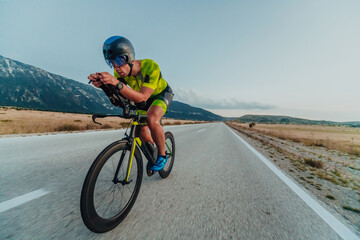 Full length portrait of an active triathlete in sportswear and with a protective helmet riding a...