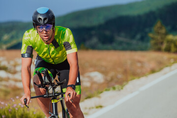 Full length portrait of an active triathlete in sportswear and with a protective helmet riding a...