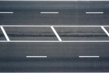 Top view of asphalt road with white strips.