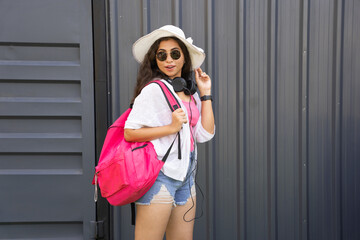 Young happy stylish Indian girl wearing trendy outfit sunglasses, hat and backpack.lifestyle fashion portrait.